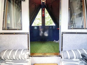 A train carriage interior with a central aisle, two upholstered seats on either side, a small rug, and a fire extinguisher mounted on the wall. - Escape II (Northwich)