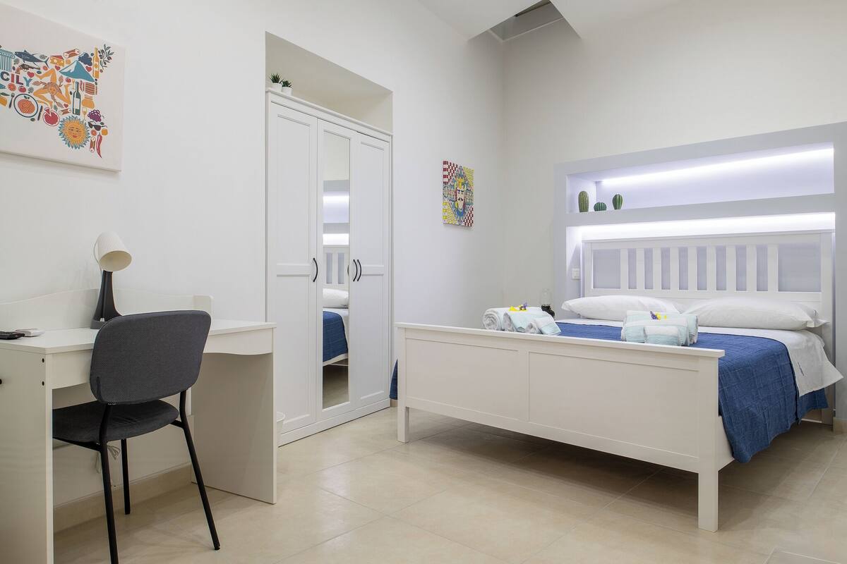 A bedroom with a bed, a desk, and a chair.