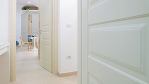 A hallway with a dining area, a door, and a light switch on the wall. - ELORO - Guest Houses (Noto)
