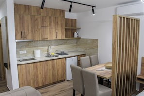 A modern kitchen with wooden cabinets, a built-in dishwasher, and a dining area with a table and chairs.