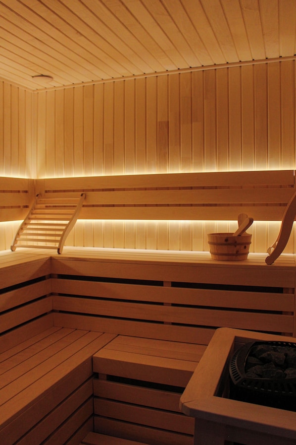 A sauna with wooden benches, a wooden ladder, and a stone basin.