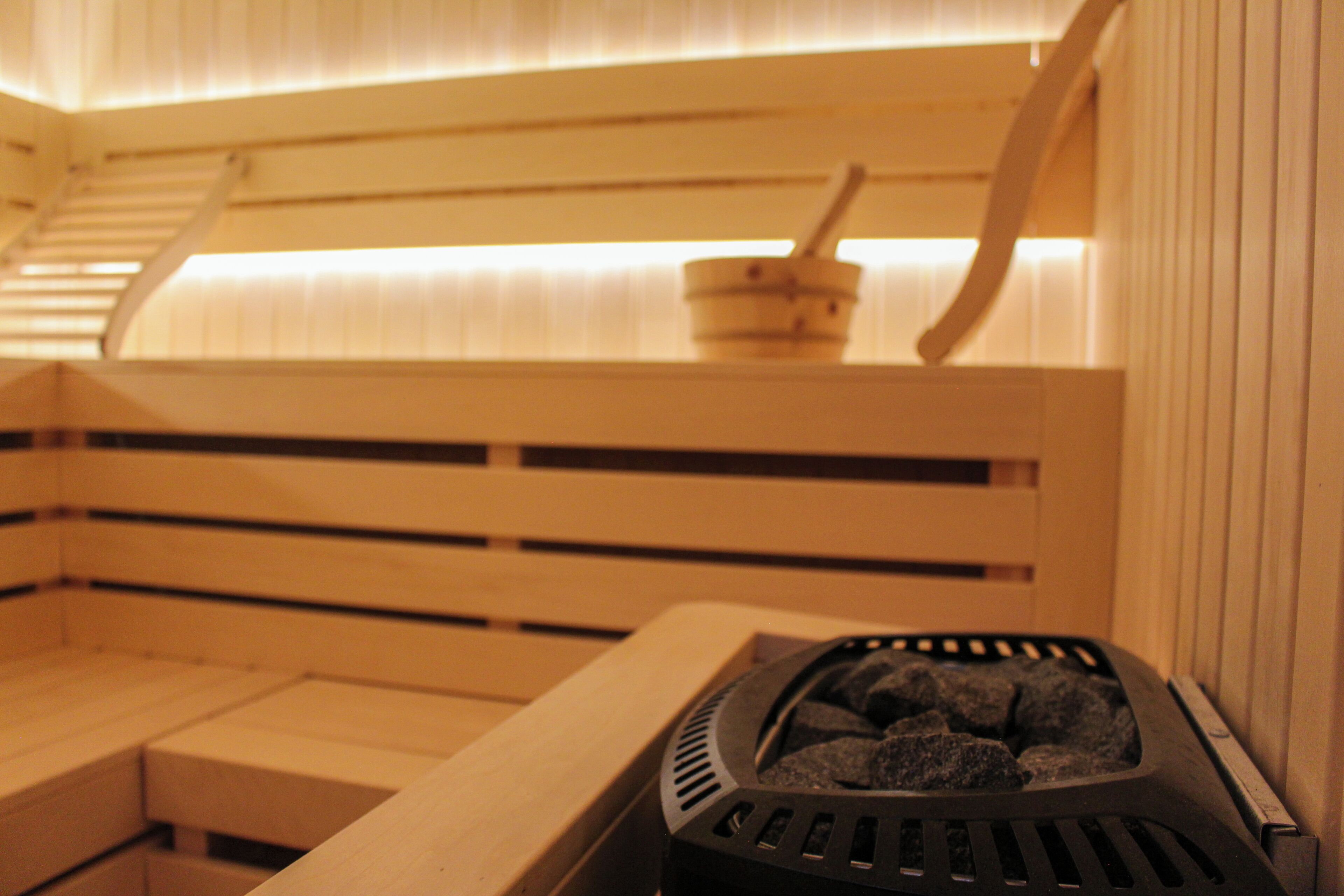 A sauna with wooden benches and a stone heating element.