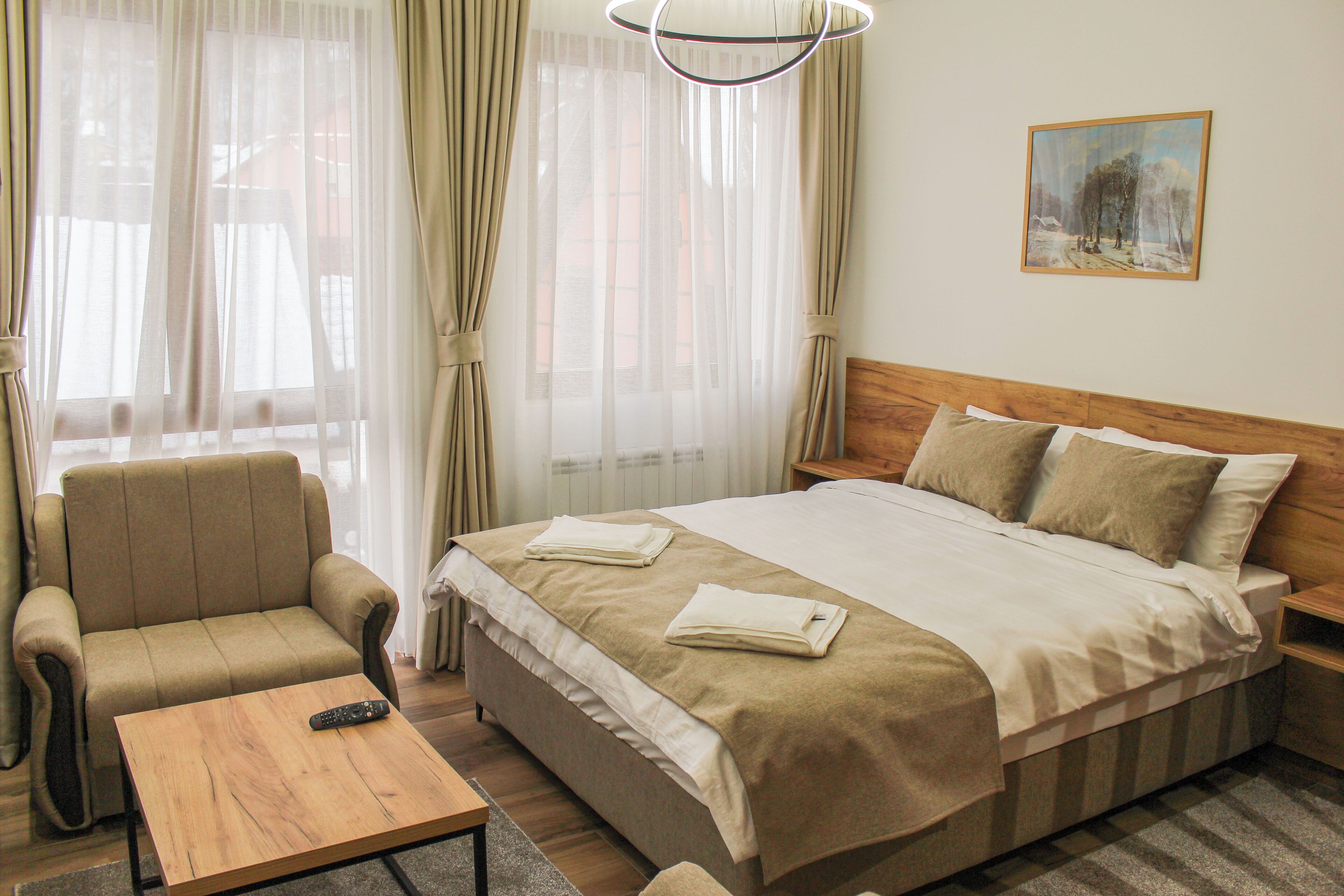 A hotel room with a bed, a sofa, a coffee table, and a painting on the wall.