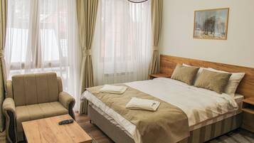 A hotel room with a bed, a sofa, a coffee table, and a painting on the wall.