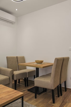 A dining area with a wooden table, four beige chairs, and a bowl on the table.