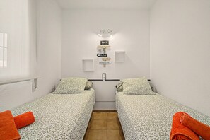 Una habitación pequeña y limpia con dos camas individuales, una lámpara en la pared y un cartel que indica un café.
