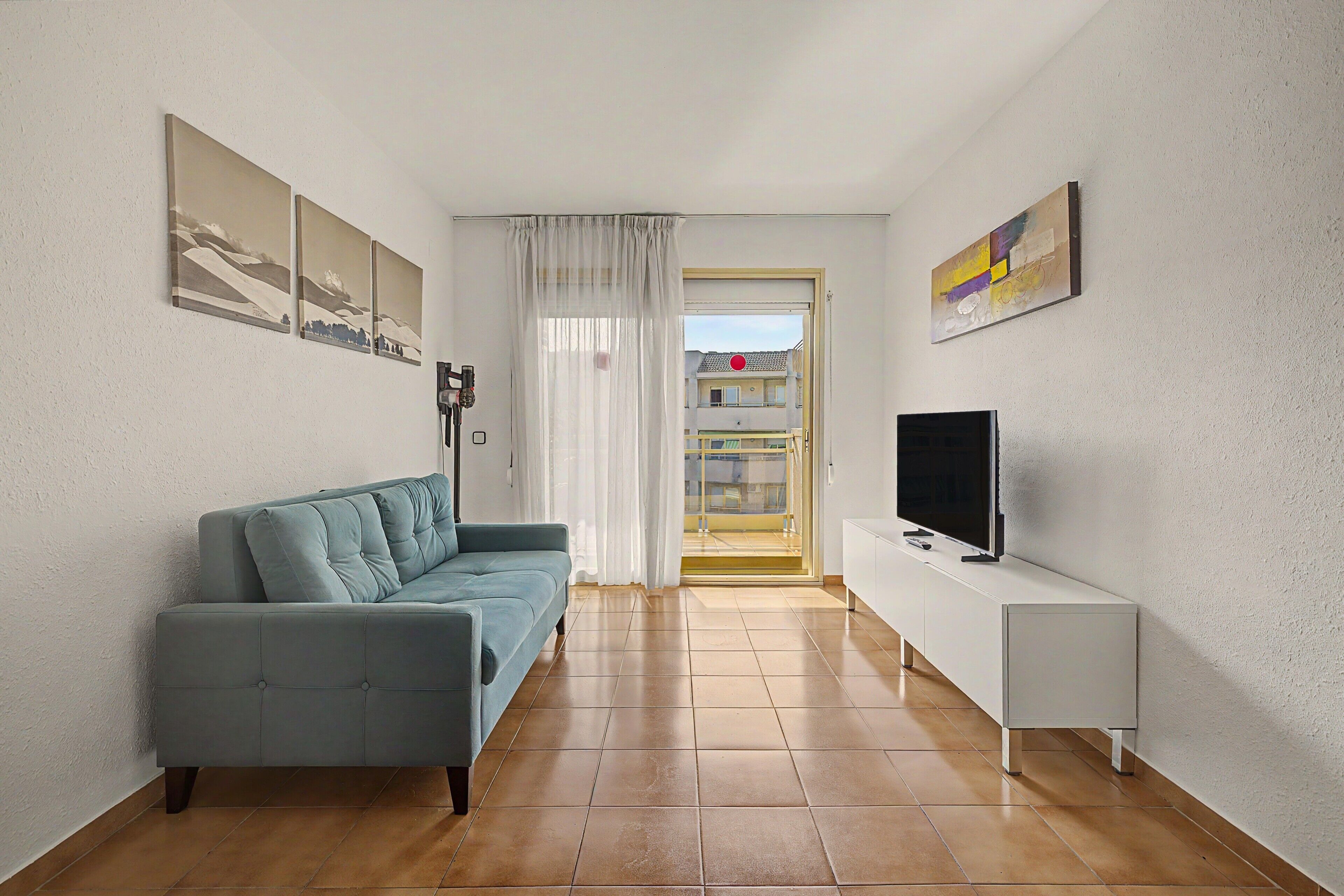 A living room with a sofa, a television, and artwork on the walls.