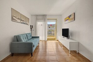 Una sala de estar con un sofá, televisor y obras de arte en las paredes.