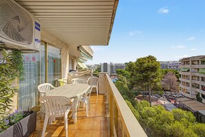 A balcony with a table and chairs, overlooking a cityscape with buildings and trees.