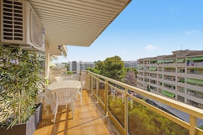 Ein Balkon mit Tisch und Stühlen, mit Blick auf ein Wohngebiet mit Gebäuden und Bäumen.