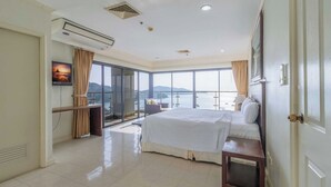Een hotelkamer met een groot bed, een bureau, een stoel en uitzicht op zee.
