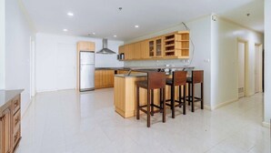 Een moderne keuken met houten kastjes, een centraal eiland met barkrukken, en een RVS afzuigkap.