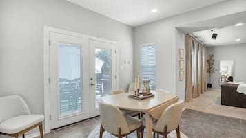 A dining area with a round table, chairs, and a view through a glass door.