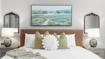Quarto com uma cama grande, duas mesas de cabeceira, um quadro e dois espelhos.