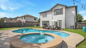 Ein Garten mit Swimmingpool, Whirlpool und einer Terrasse mit Gartenmöbeln.
