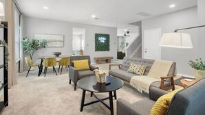 Ein modernes Wohnzimmer mit einer Couch, Sesseln, einem Couchtisch und einem Essbereich mit Stühlen und einem Tisch.