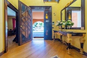 A hotel lobby with a wooden floor, a large ornate door, a reception desk, and a mirror with a vase of flowers. - Luxurious, swimming pool, home theater, elevator, sauna, fitness area, game room (Mascalucia)