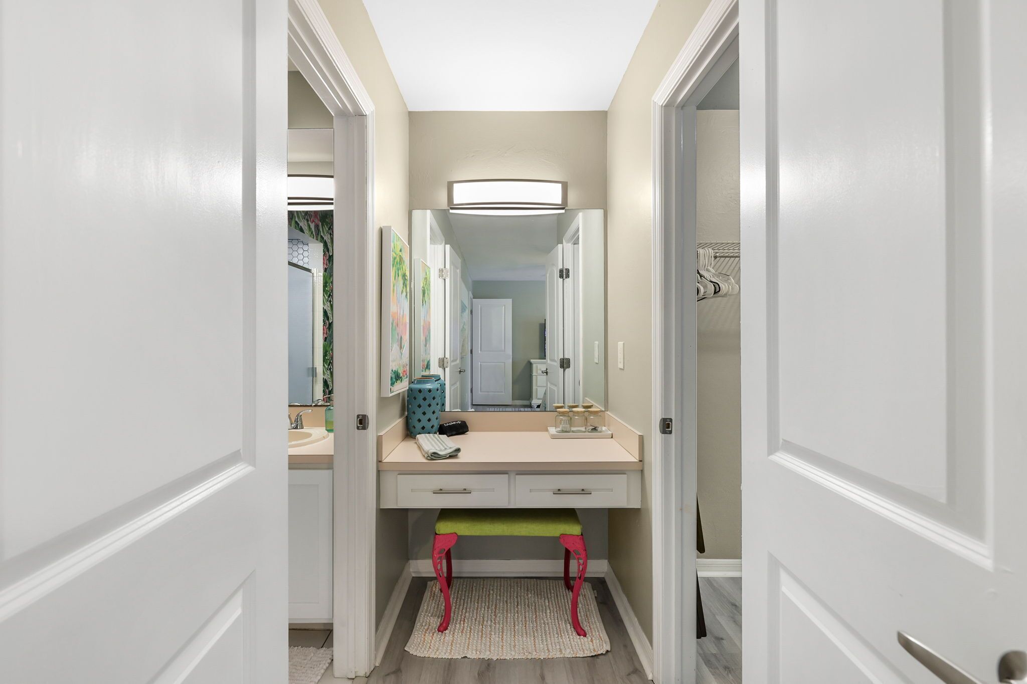 A narrow hallway with a vanity, a mirror, and a bench.