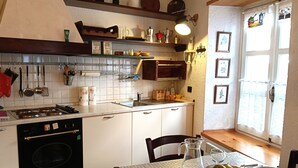 Ett kök med en spis, diskho och ett matbord dukat med tallrikar och glas.