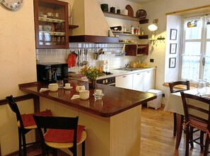 A kitchen with a central island, wooden chairs, a dining table, and a window with curtains. - House of the Temple - Perfect for 4 people (Briançon)