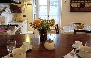 Ein Esstisch mit einer Blumenvase, einem Teekessel und verschiedenen Tassen und Gläsern.