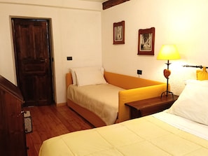 A room with a bed, a bedside table with a lamp, a wooden door, and two framed pictures on the wall. - House of the Temple - Perfect for 4 people (Briançon)