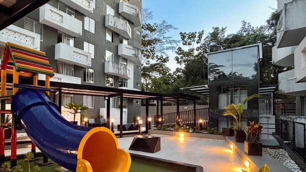 A playground with a slide and a climbing structure, surrounded by a courtyard with potted plants and a pathway. - Amber Sky Apartment (Armenia)