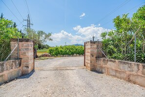 Ein ländliches Tor mit Steinmauern, einem Kiesweg und einem Weinberg im Hintergrund.