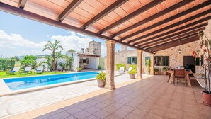 A covered outdoor area with a swimming pool, lounge chairs, and a dining table. - Villa Ca Na Maria - By Dream Villas Pollensa (Pollensa)