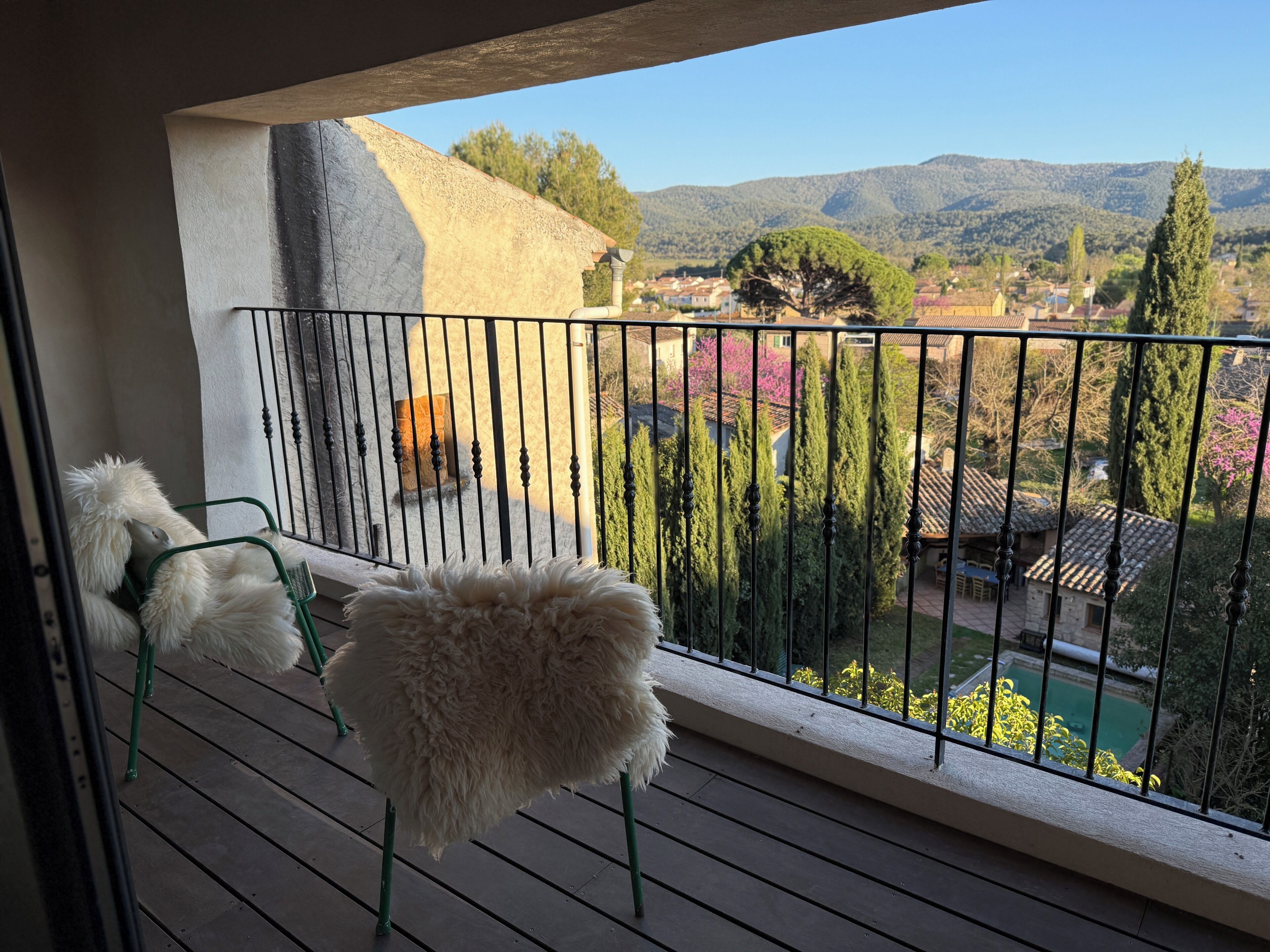 Un balcon avec vue sur un paysage montagneux, une piscine et un jardin.