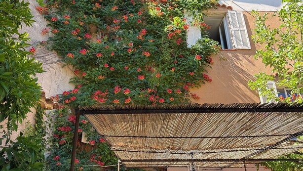 A building with a tiled roof, a balcony with a woven shade, and a window with a view. - The Hôtel Particulier 1900, a 500m² country house in the Var region (Pignans)