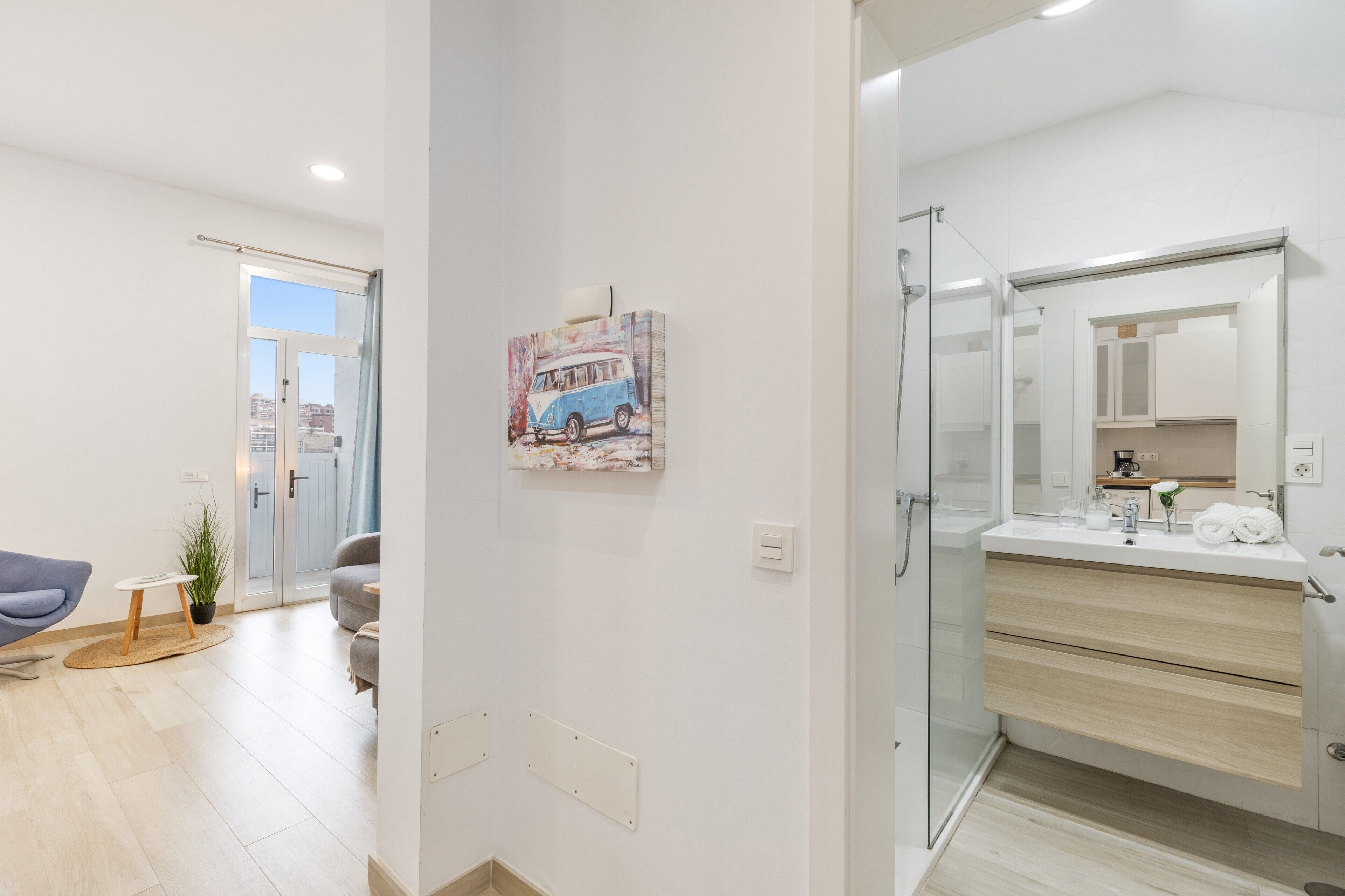Un baño moderno con cabina de ducha de vidrio, un espejo grande y un lavabo blanco.