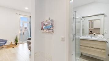 Un baño moderno con cabina de ducha de vidrio, un espejo grande y un lavabo blanco.