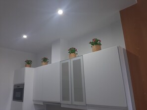Eine Küche mit weißen Schränken, einem eingebauten Backofen und drei Korbmöbeln mit Blumen auf den oberen Schränken.