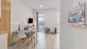 Una cocina moderna con comedor, televisor en la pared y un amplio ventanal.