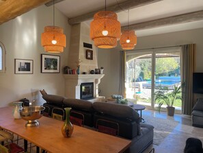 A living room with a fireplace, a dining table, and a sofa. - THE PROPERTIES: Air-conditioned and with a heated pool, in the Alpilles park (Saint-Rémy-de-Provence)
