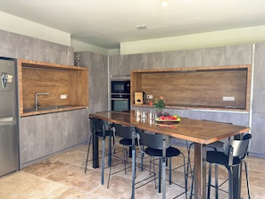 Une cuisine moderne avec un îlot central en bois, des chaises noires et des appareils électroménagers en acier inoxydable.