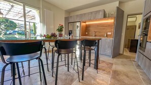 Une cuisine moderne dotée d’un îlot central, de tabourets de bar et offrant une vue sur l’extérieur.