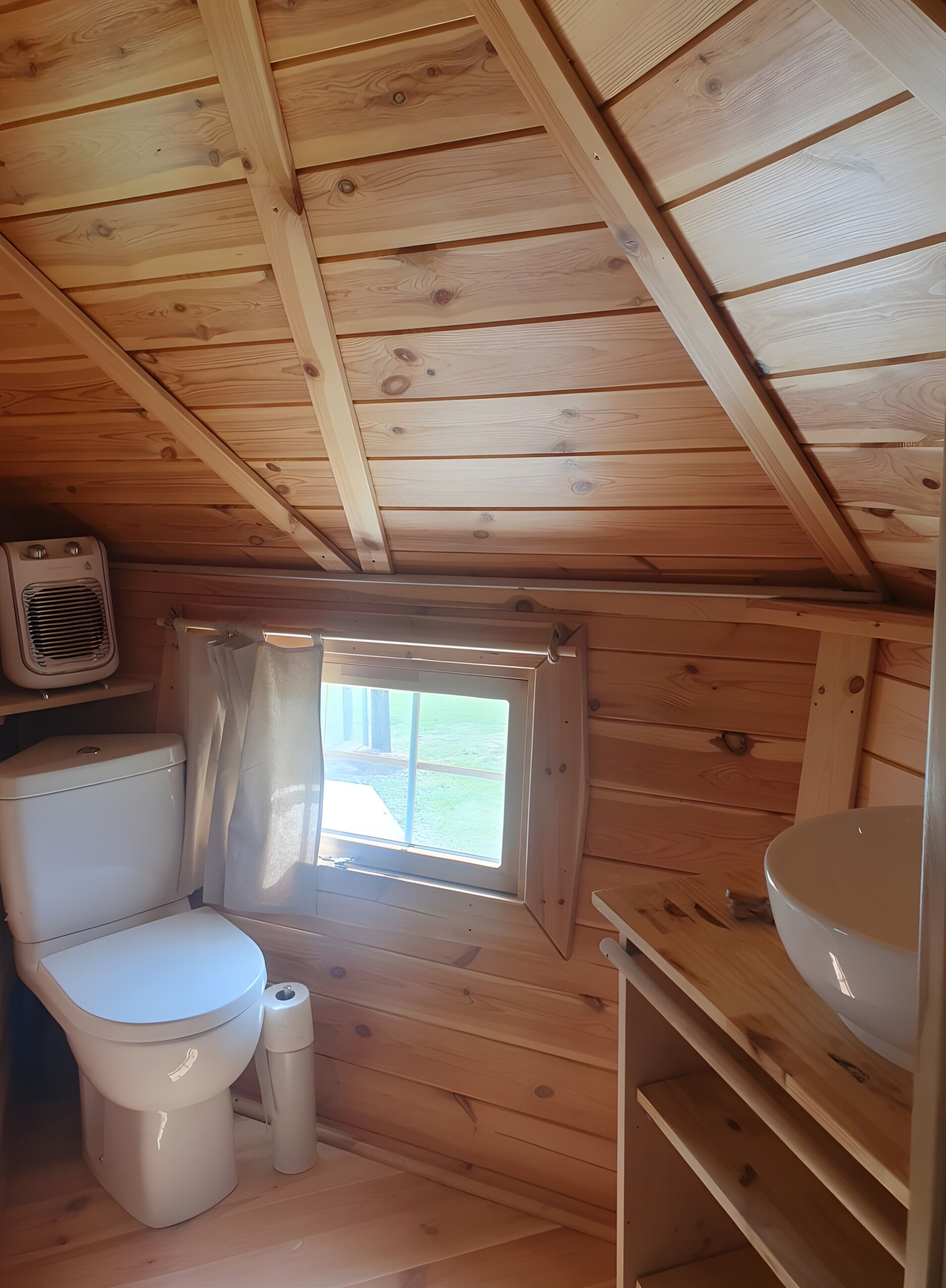 Ett litet badrum med träpanel på väggarna, utrustat med toalett, handfat och ett fönster.