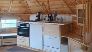 Ein Holzinnenraum mit Küchenzeile, inklusive Herd, Backofen und Schränken.
