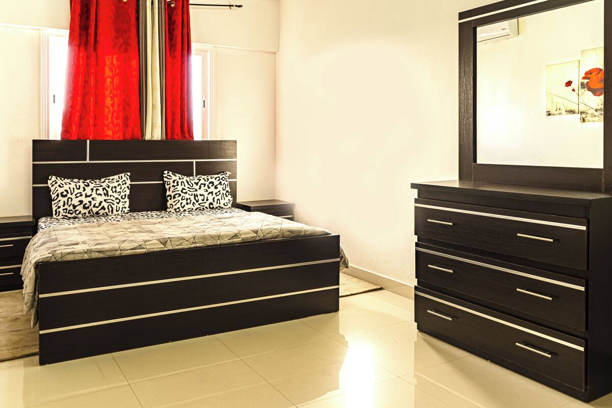 Un dormitorio con cama, mesitas de noche, cómoda y espejo.