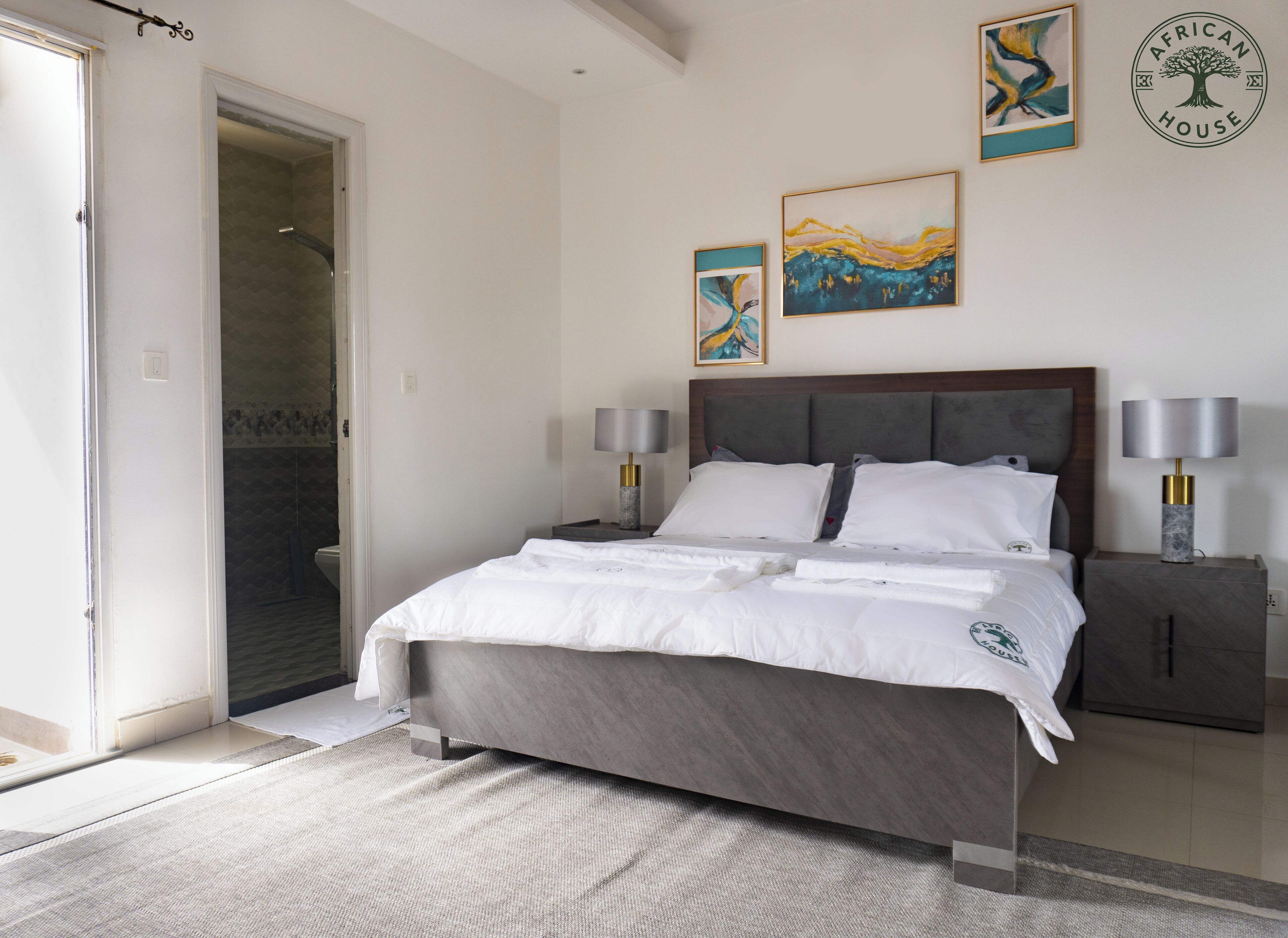 A bedroom with a bed, two bedside tables, a headboard, and artwork on the wall.