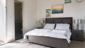 A bedroom with a bed, two bedside tables, a headboard, and artwork on the wall.