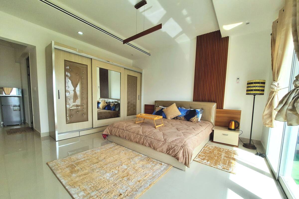 Un dormitorio moderno con una cama grande, un armario, una mesita de noche y una lámpara de pie.