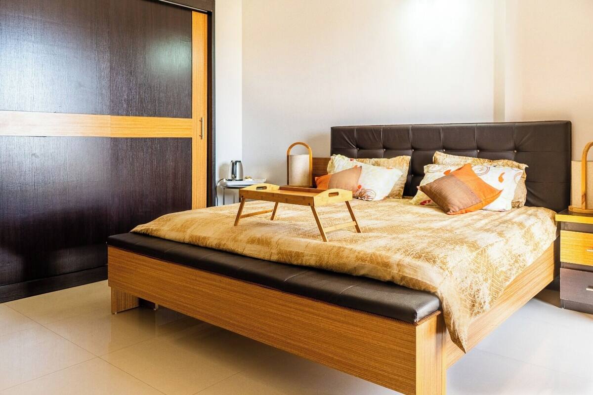 Un dormitorio moderno con estructura de cama de madera, una mesita de noche y un buró.
