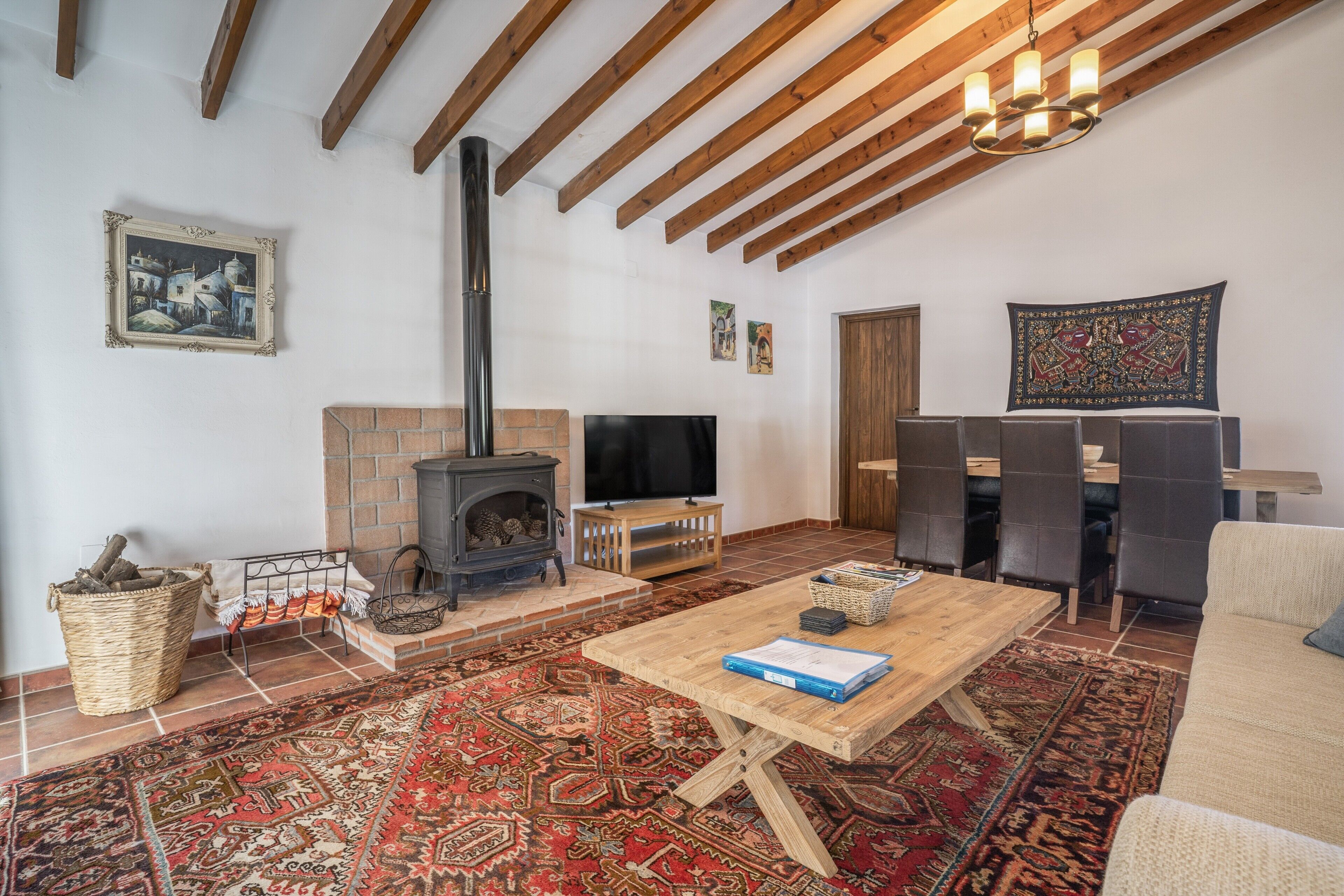 Una sala acogedora con chimenea, televisor y comedor con sillas.