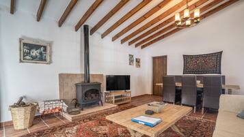 Una sala acogedora con chimenea, televisor y comedor con sillas.