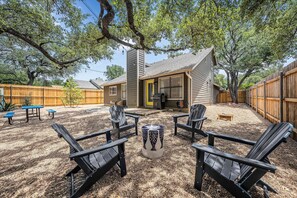 A backyard with Adirondack chairs, a fire pit, and a wooden deck. - Stylish Backyard Retreat BBQ Workspace (Austin)