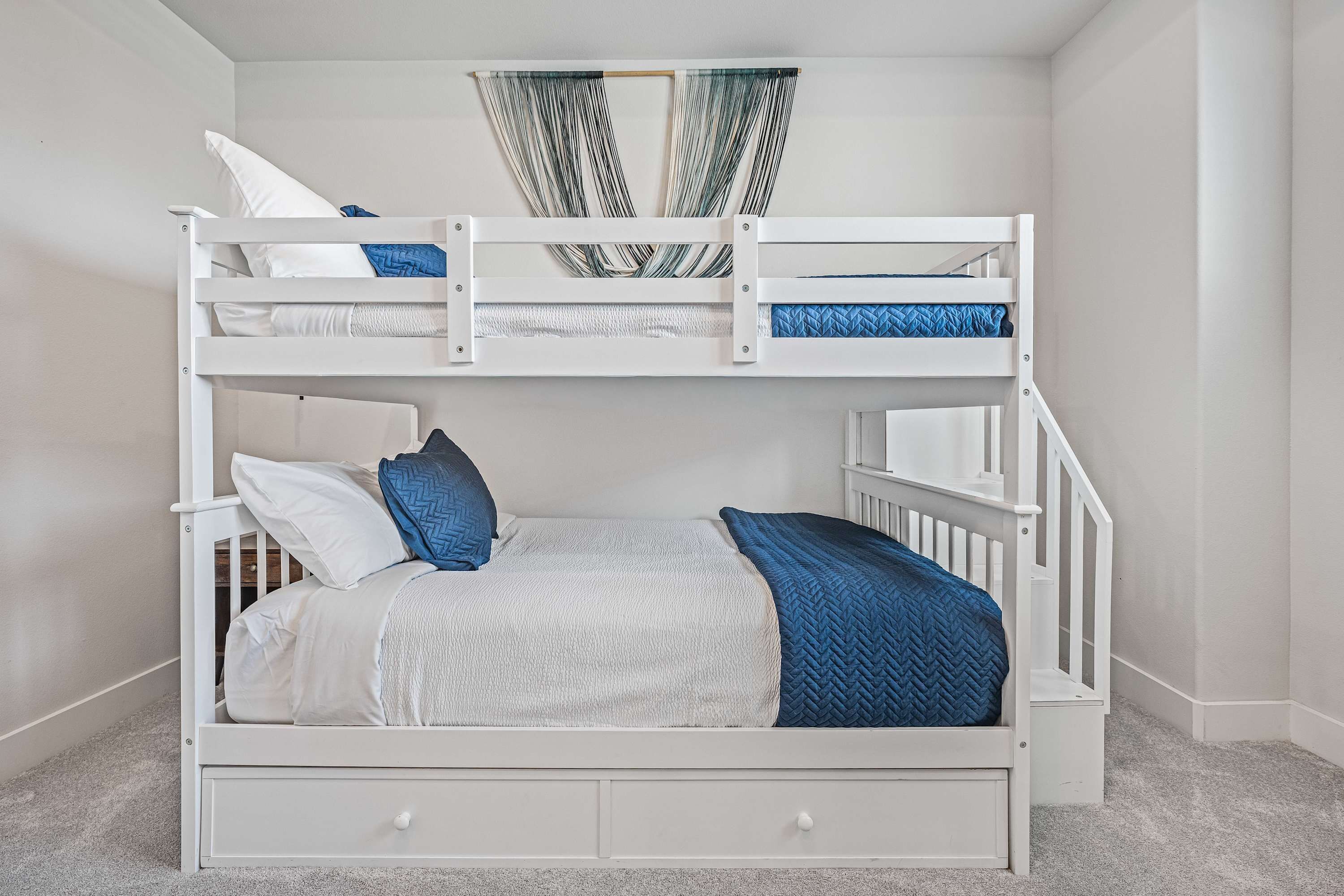 A bunk bed with a lower bunk, a small ladder, and a storage drawer.