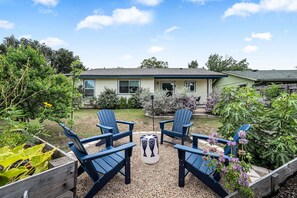 Ein Haus mit Garten, zwei Adirondack-Stühlen und einer Holzterrasse.